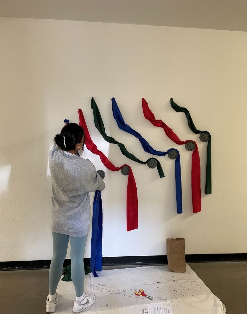 a student works with heavy sculpture equipment in a safety mask