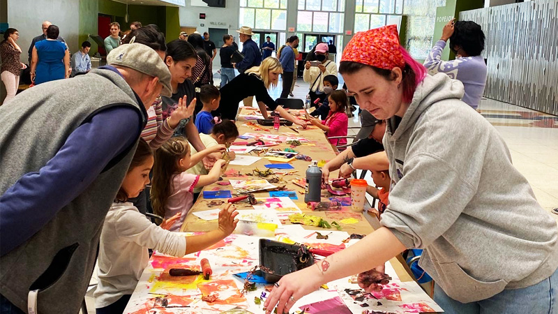 parents and children work at a large table making art