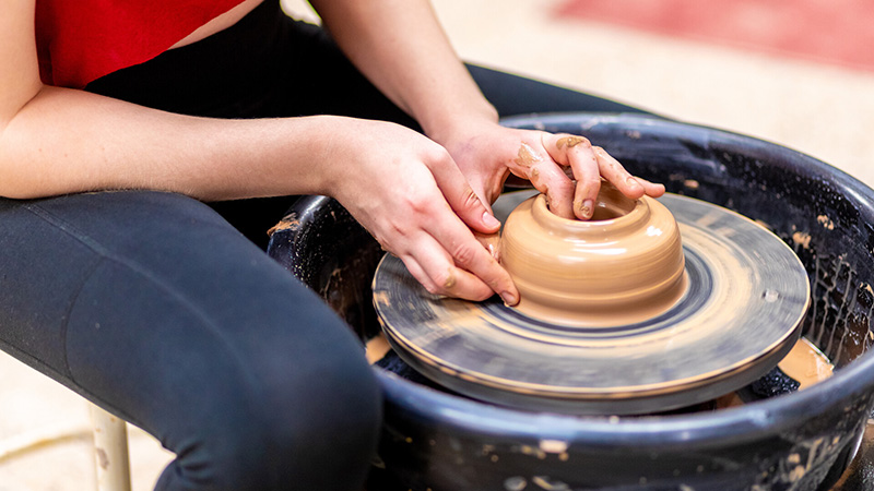 a potter's hands throwing on the wheel