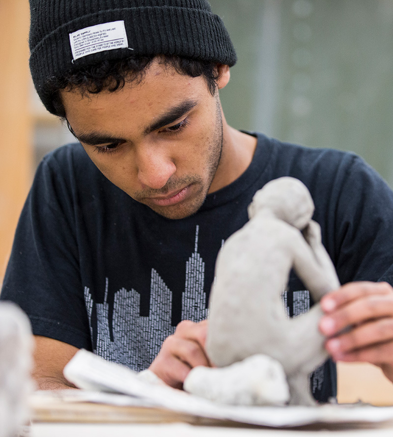art student hand building a sculpture out of clay
