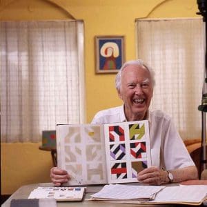 Frederick Hammersley smiling holding a book open of some of his works