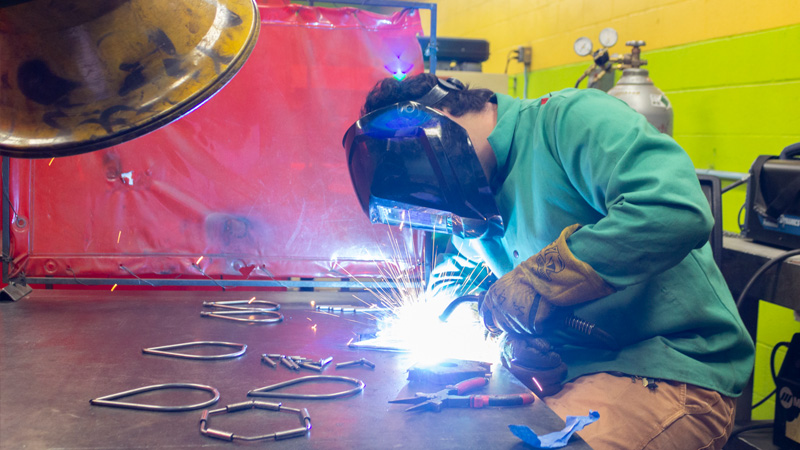 A welder works in the metal sculpture lab