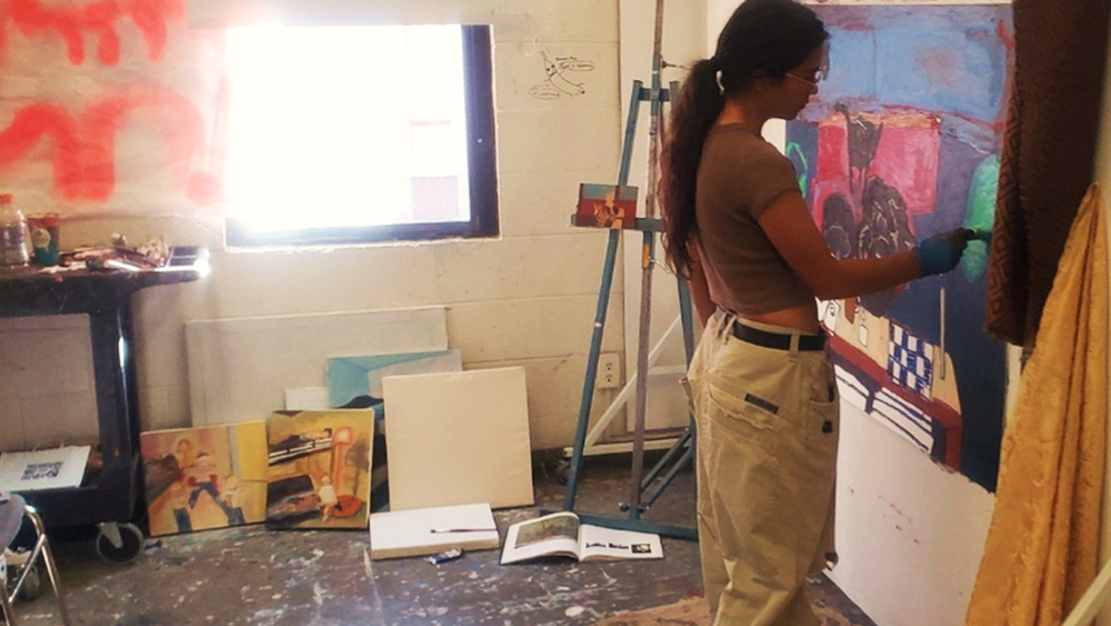 Mikaila Dart working on a painting in an art studio
