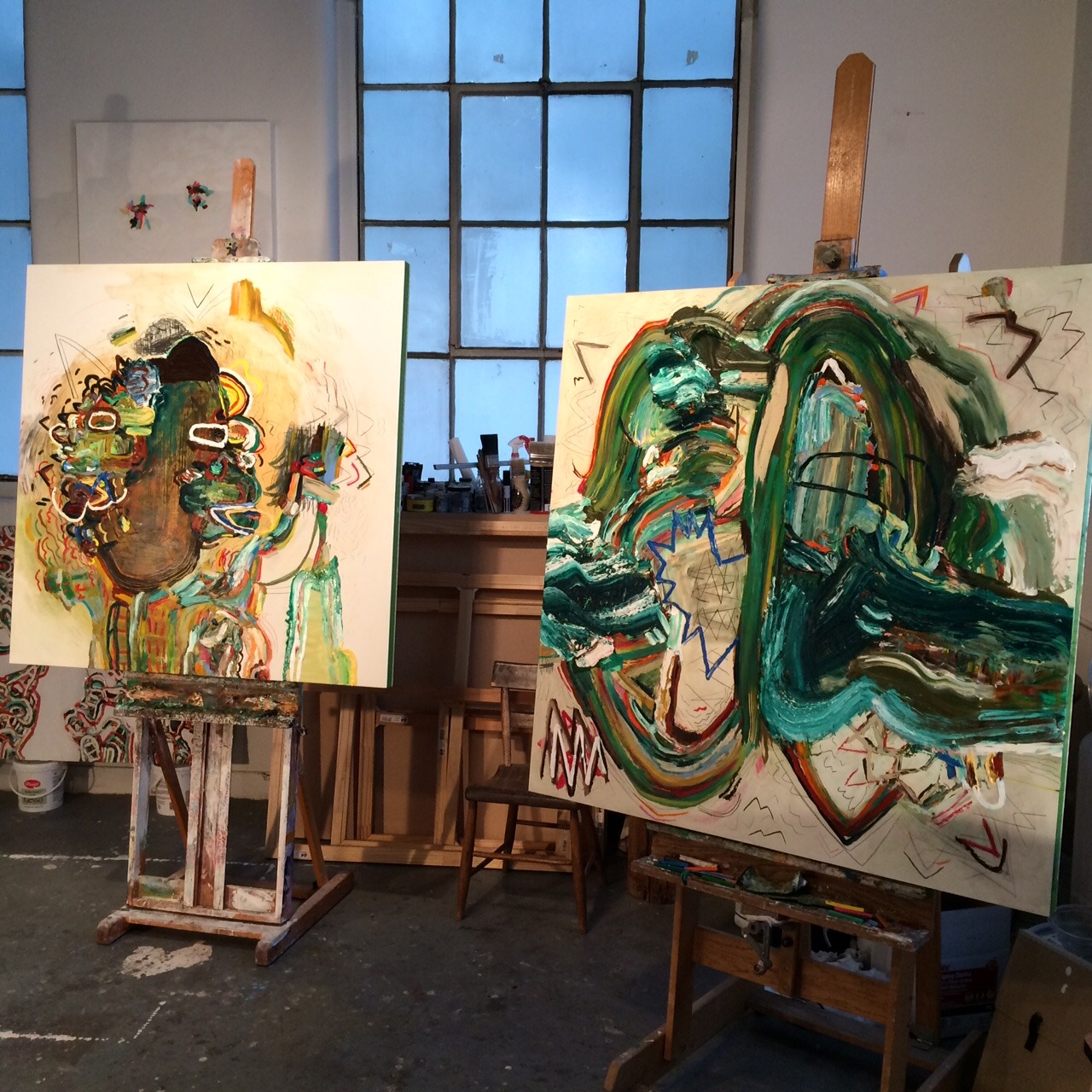 large paintings in progress on easels in a studio