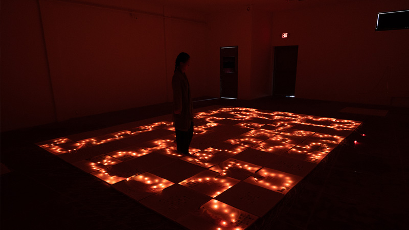a person standing on top of an intricately lighted floor installation