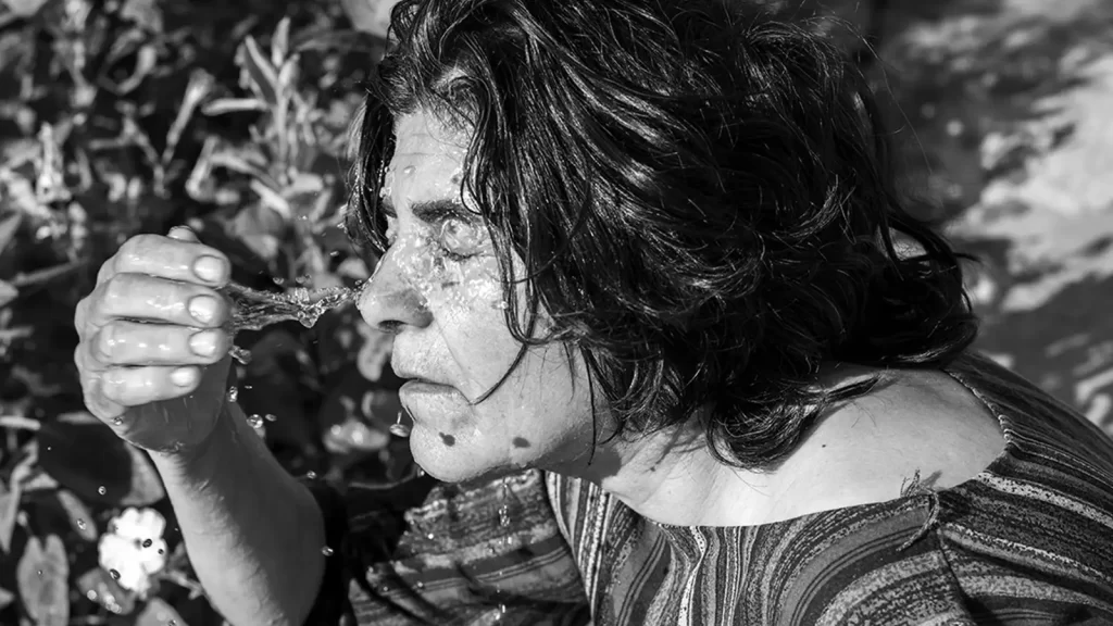 Black and white photo of a woman splashing water on her face