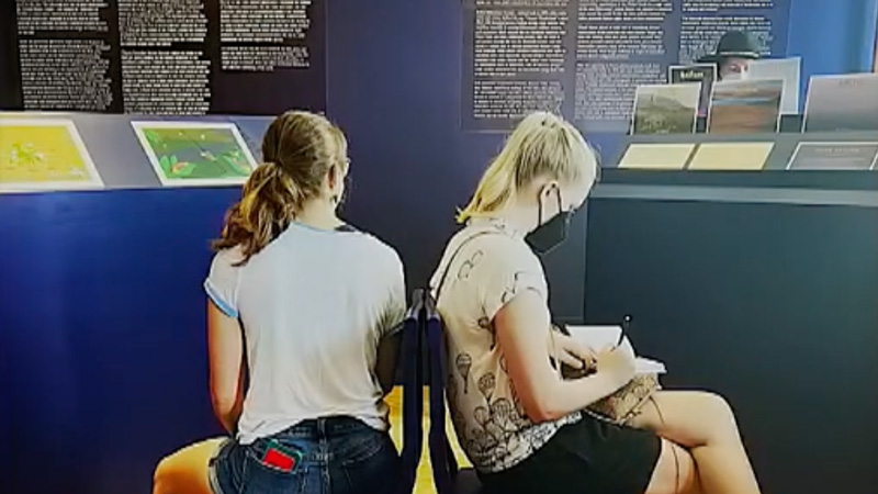 two women seated back to back in library